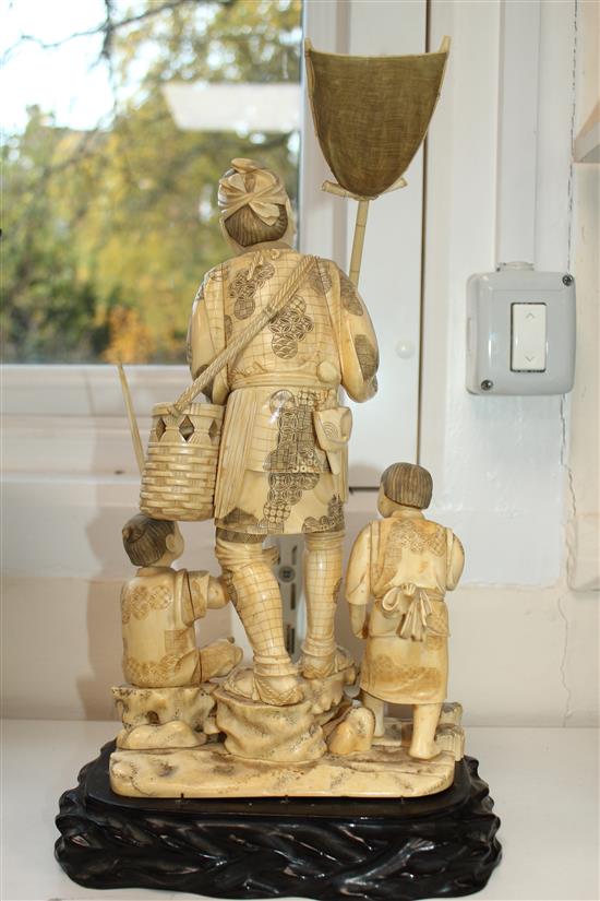 A large Japanese sectional walrus ivory okimono of a fisherman and two boys, early 20th century height including wood stand, 40cm